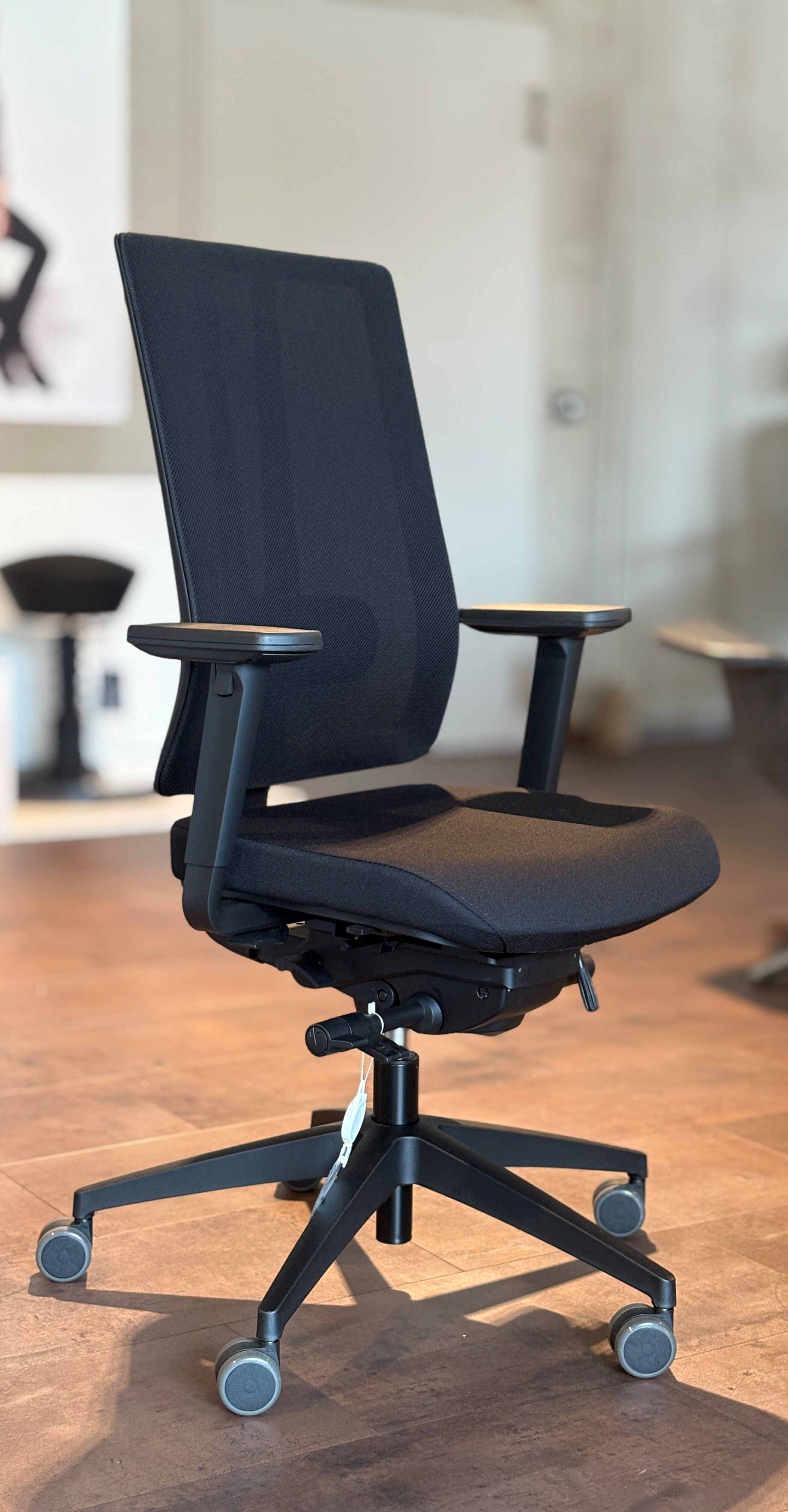 Ergonomischer Bürostuhl in Schwarz mit verstellbaren Armlehnen und Rollen, betont dynamisches Sitzen und Komfort.