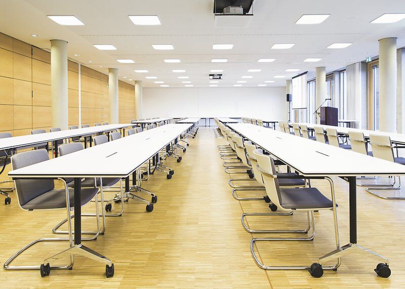 Leerer Konferenzraum mit ergonomischen Stühlen und Tischen, ideal für professionelle Meetings und Präsentationen.