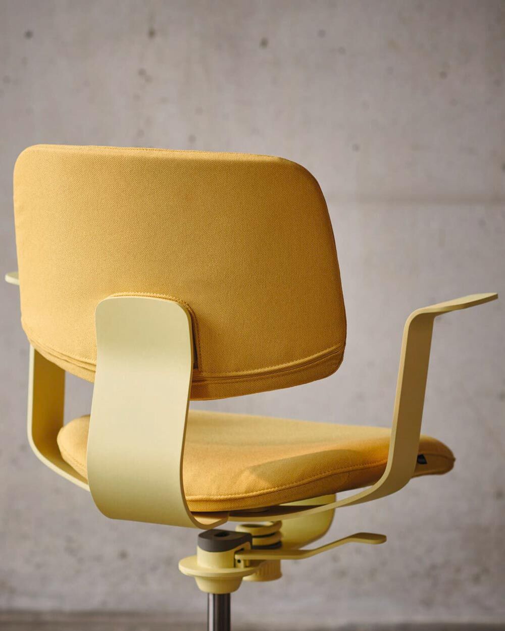 Ergonomischer gelber Bürostuhl mit verstellbarer Rückenlehne und Armlehnen, vor einer neutralen Wand fotografiert.