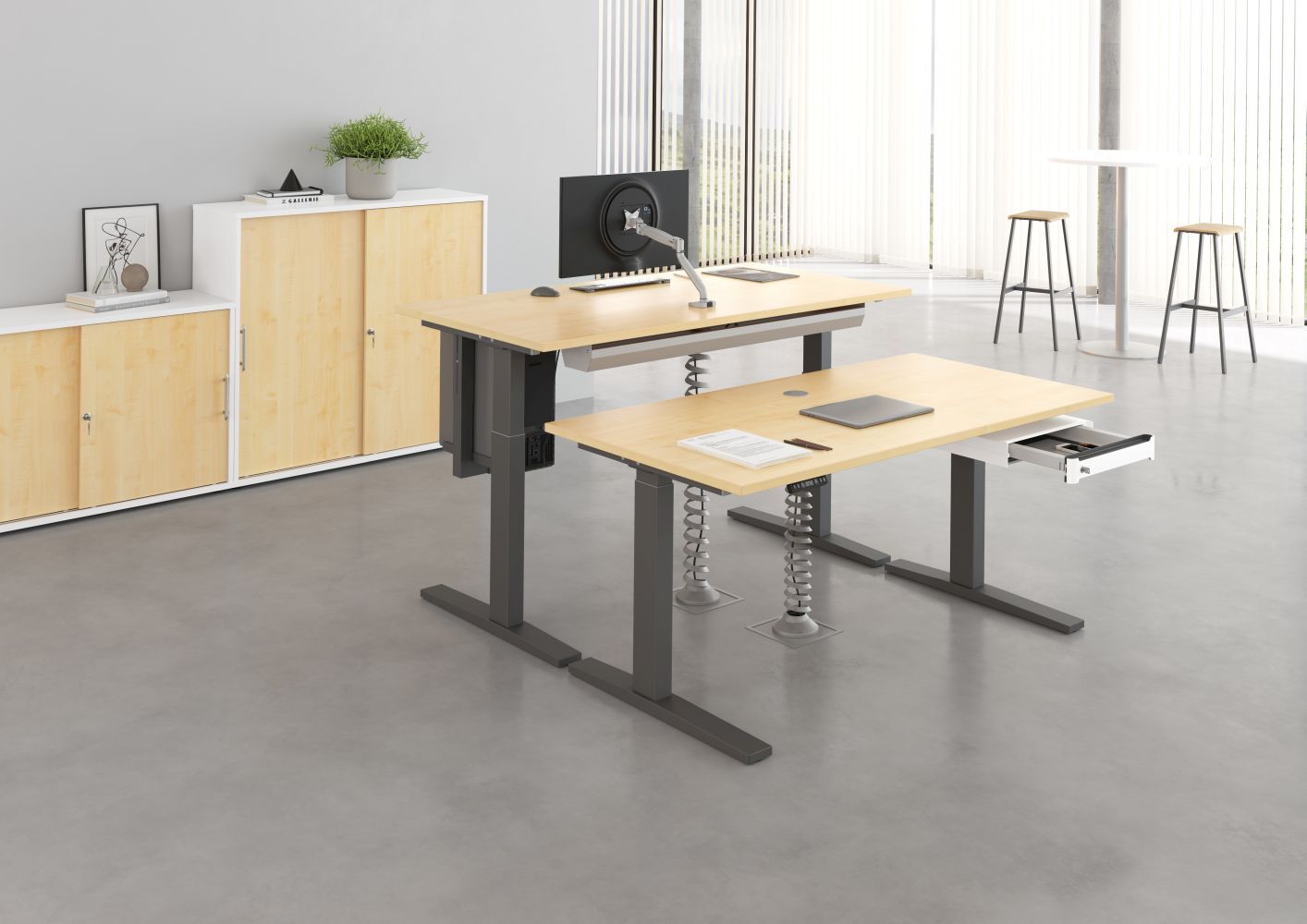 Ergonomische Bürotische mit höhenverstellbaren Beinen, Laptop und Monitorarm in modernem Bürobereich.