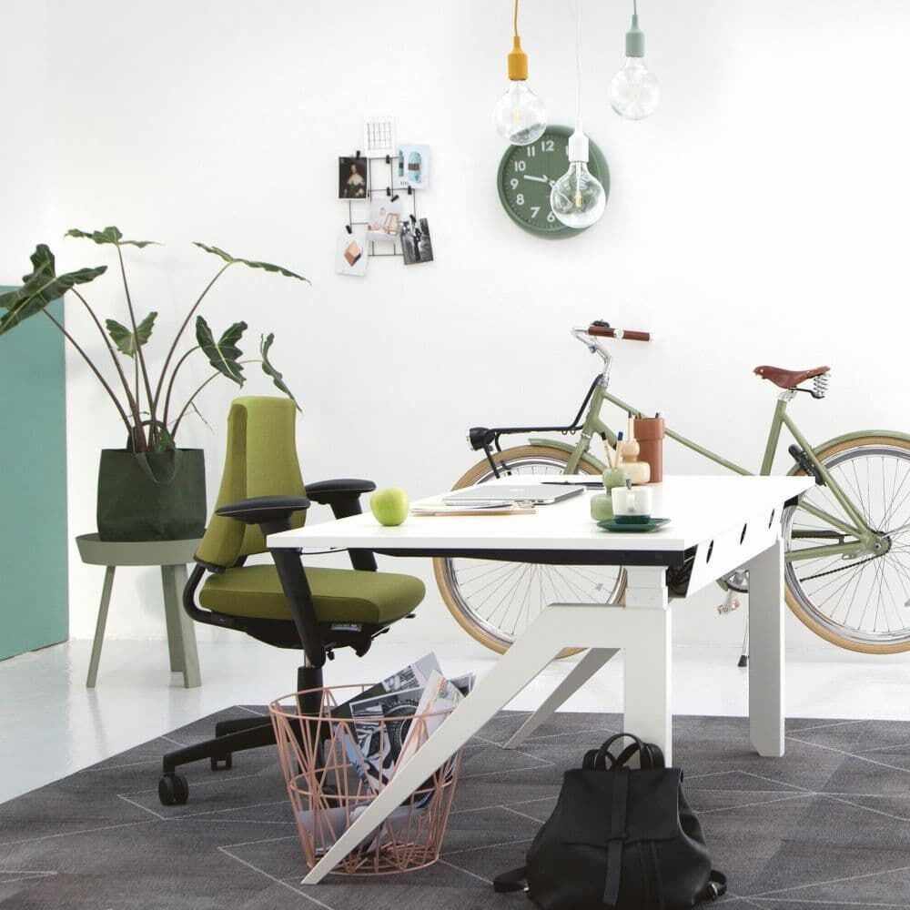 Modernes Büro mit grünem ergonomischen Stuhl, weißem Tisch, Fahrrad und Pflanzen, betont Bewegung und Gesundheit.