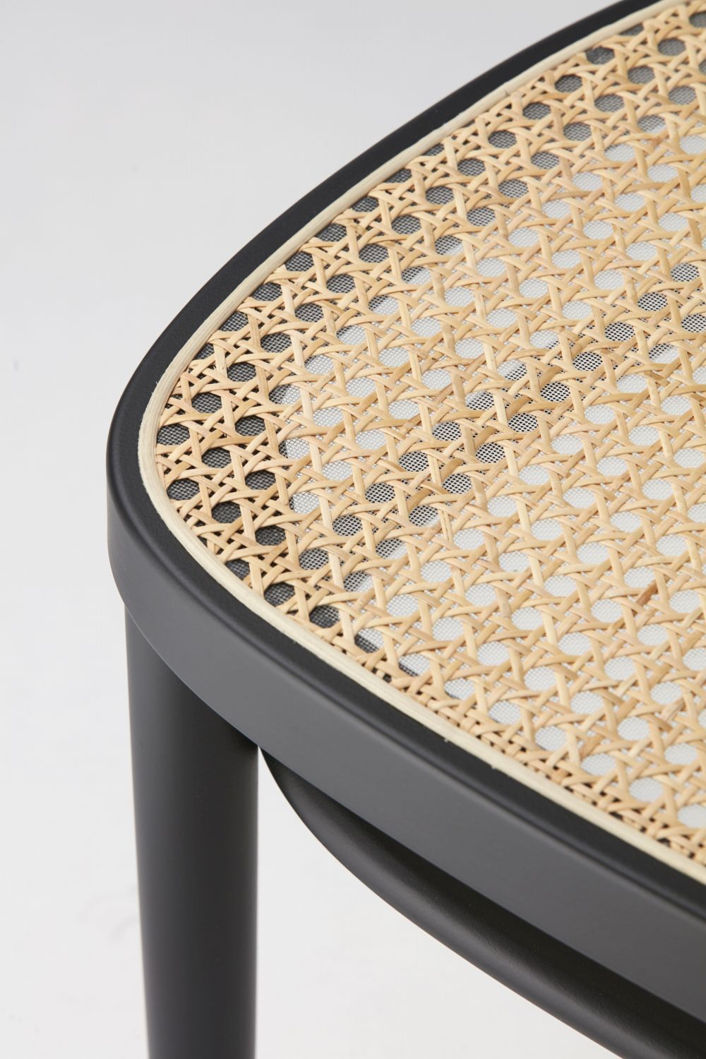 Nahaufnahme eines ergonomischen Stuhles mit einem geflochtenen Sitz aus Naturmaterialien und einem schwarzen Rahmen.