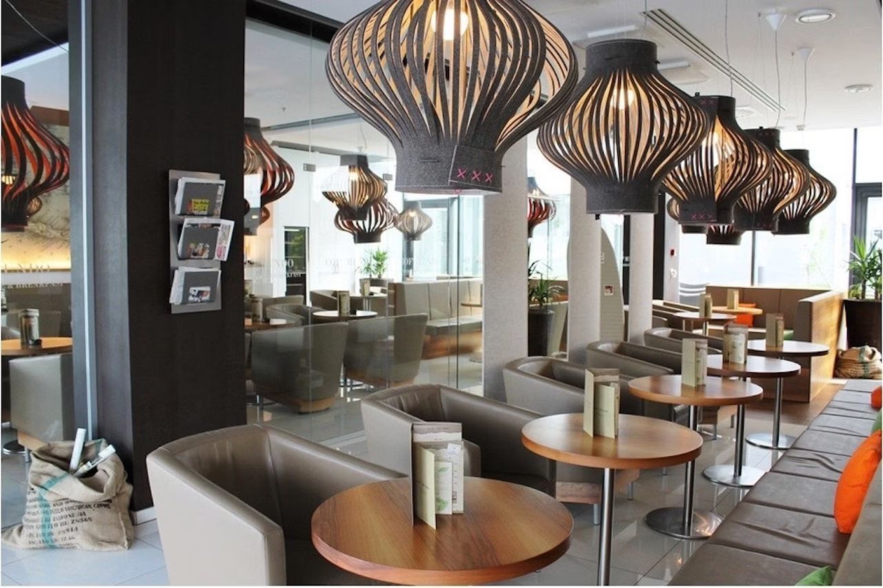 Moderne Lounge mit Design-Lampen, runden Holztischen und bequemen Ledersesseln in einem eleganten Ambiente.