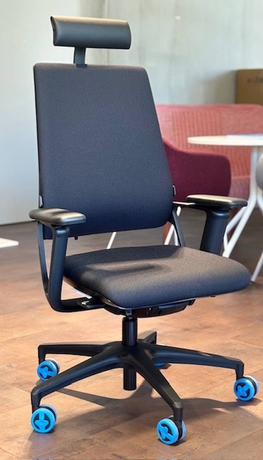 Ergonomischer Bürostuhl mit Kopfstütze und blauen Rollen, ideal für gesundes dynamisches Sitzen im Büro.