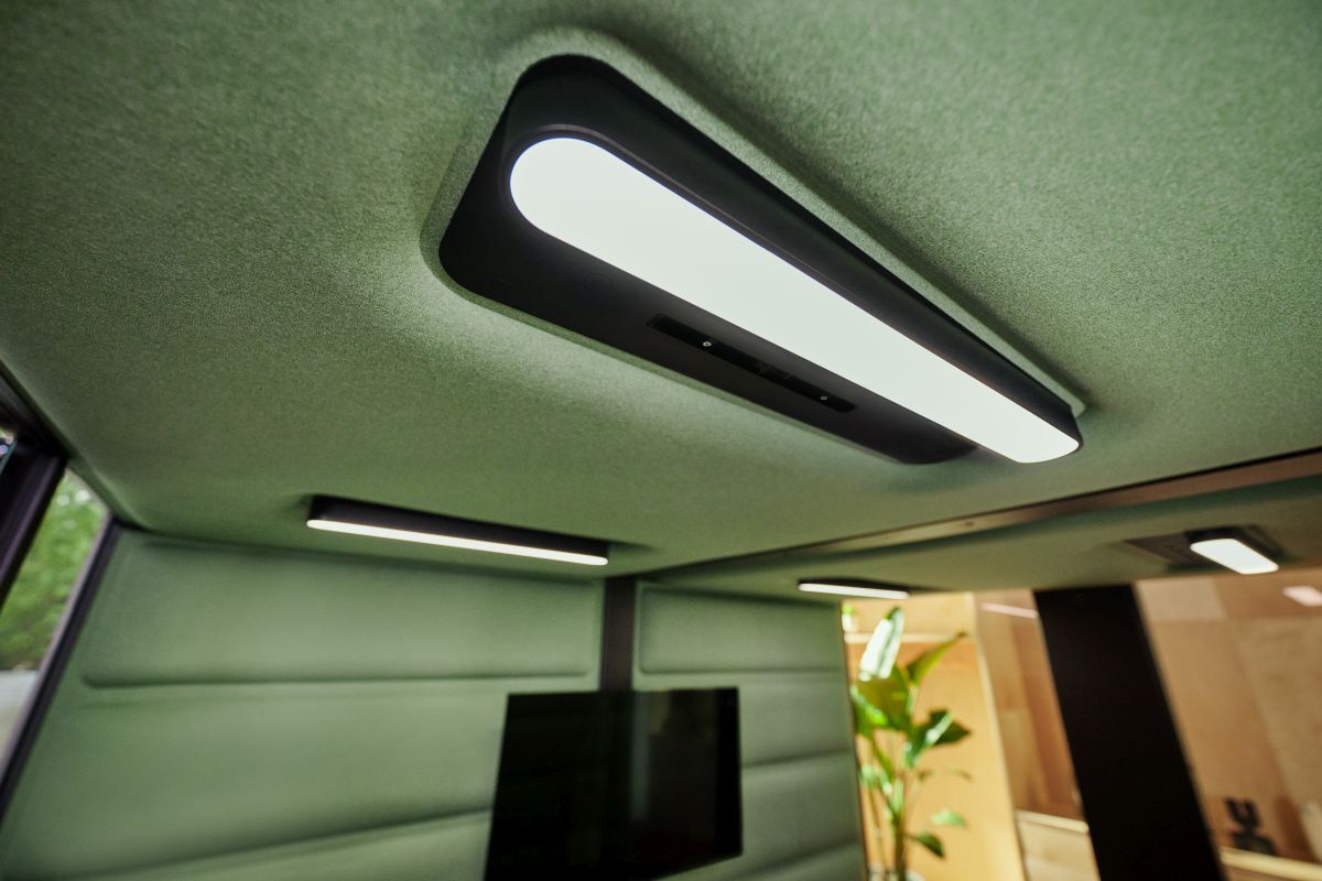 Modernes, grünes Büro mit eleganter Deckenbeleuchtung und Pflanzen, das ein angenehmes Arbeitsumfeld schafft.