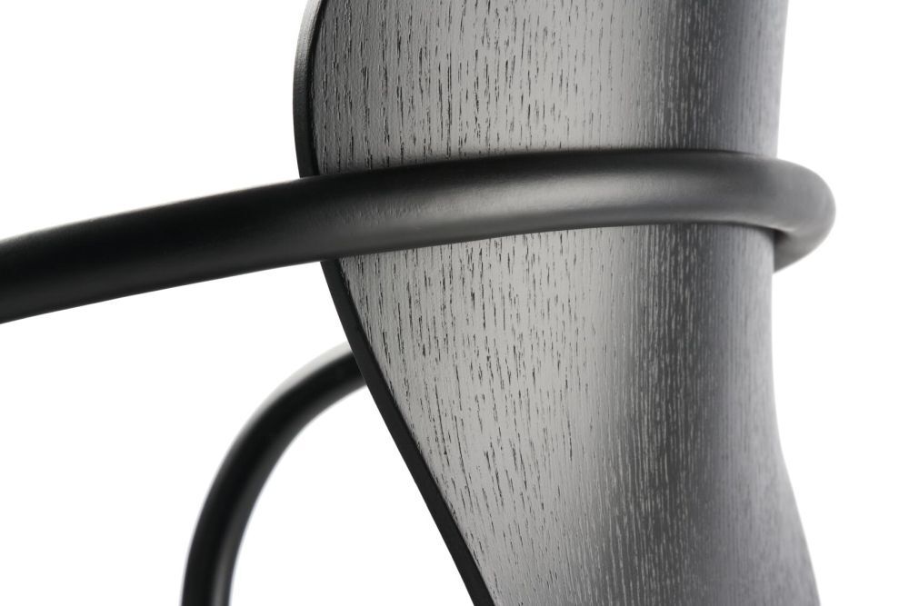 Detailaufnahme eines ergonomischen Stuhldesigns mit gebogenem Holz und mattschwarzem Metallrahmen.