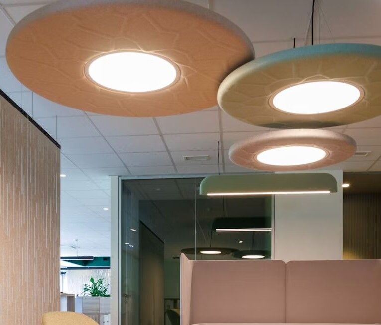 Modern gestalteter Büroraum mit stilvollen, runden Deckenleuchten und hellen, ergonomischen Sitzgelegenheiten.