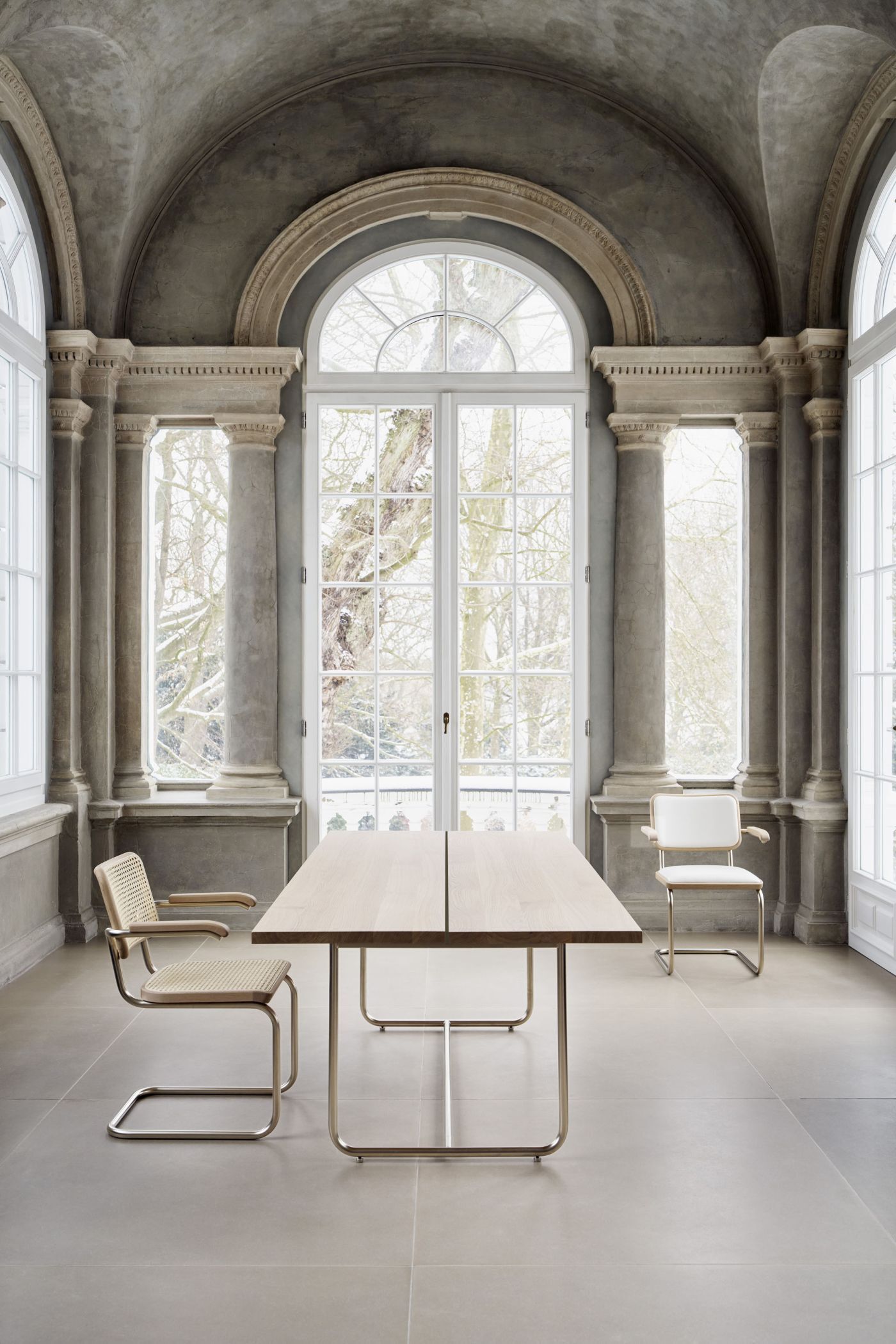 Ergonomischer Tisch und Stühle in elegantem, lichtdurchflutetem Raum mit großen Fenstern und klassischer Architektur.