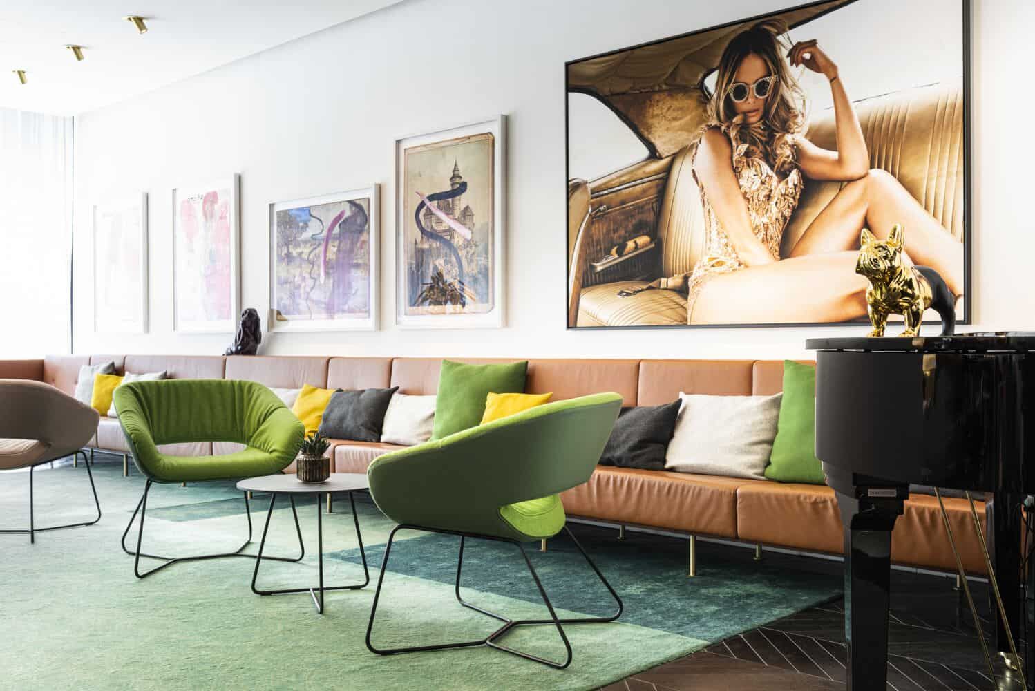 Moderner Lounge-Bereich mit grünen Sesseln, Kunstwerken an der Wand und Dekoration auf schwarzem Klavier.