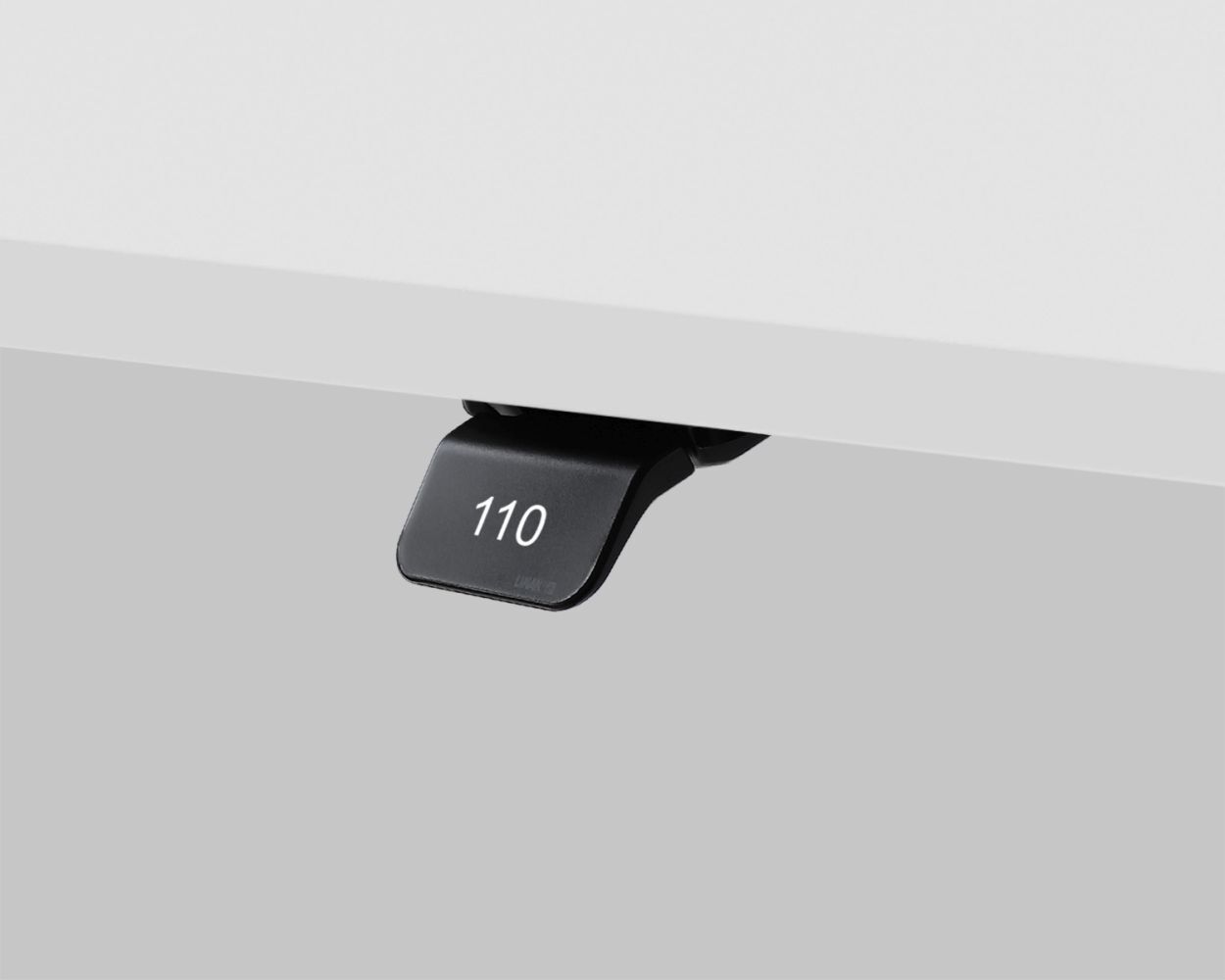 Nahaufnahme eines schwarzen Hebels unter einem Tisch mit der Aufschrift '110'.