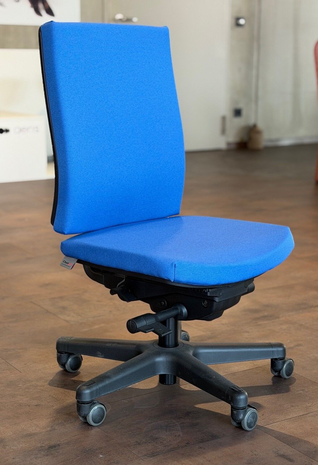Hochwertiger ergonomischer Bürostuhl mit blauem Stoffbezug auf einem Holzfußboden, geeignet für dynamisches Sitzen.