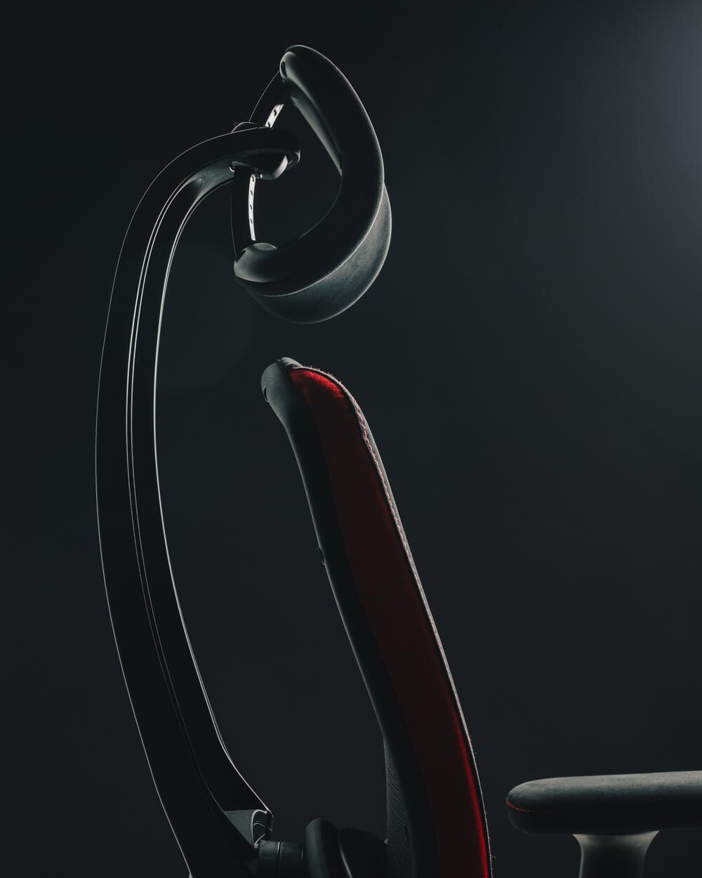 Ergonomischer Bürostuhl in Nahaufnahme, zeigt Kopfstütze und Rückenlehne vor dunklem Hintergrund.