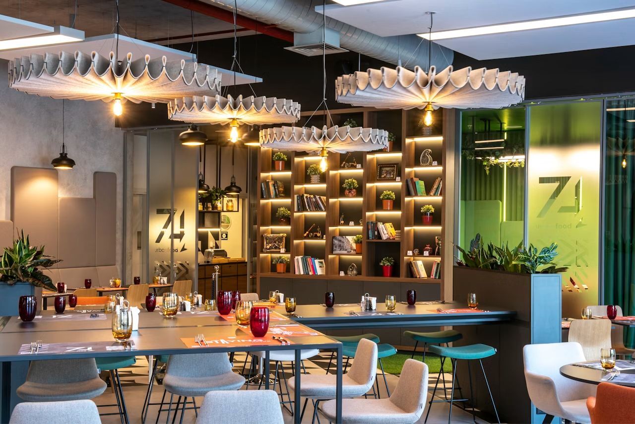 Modernes Büro mit stilvoller Beleuchtung, ergonomischen Stühlen und Regalen voller Bücher und Pflanzen.