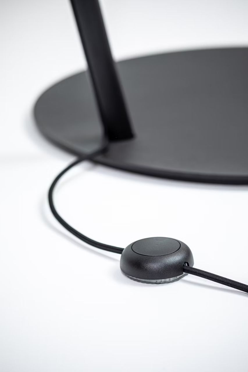 Nahaufnahme eines ergonomischen Schreibtischs mit Kabel und Schalter auf einer schwarzen Basis.