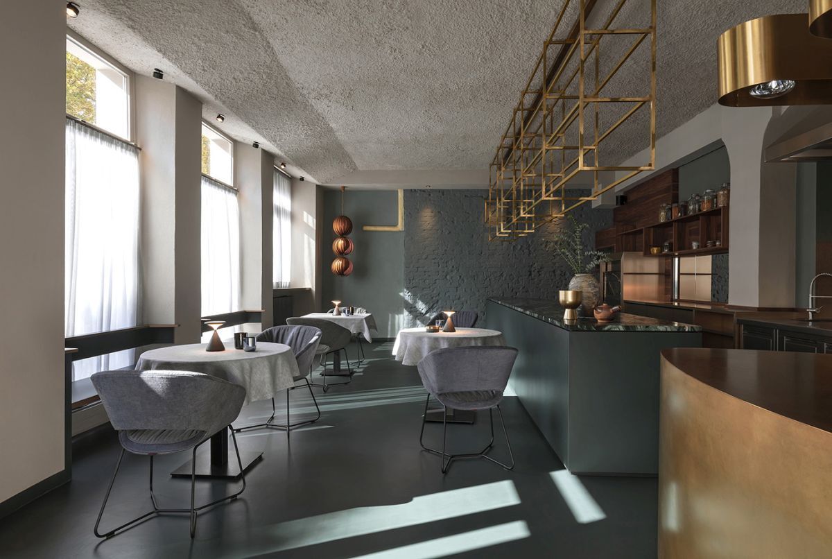 Elegantes Café mit runden Tischen, modernen Stühlen und goldenen Dekoelementen an der Decke.