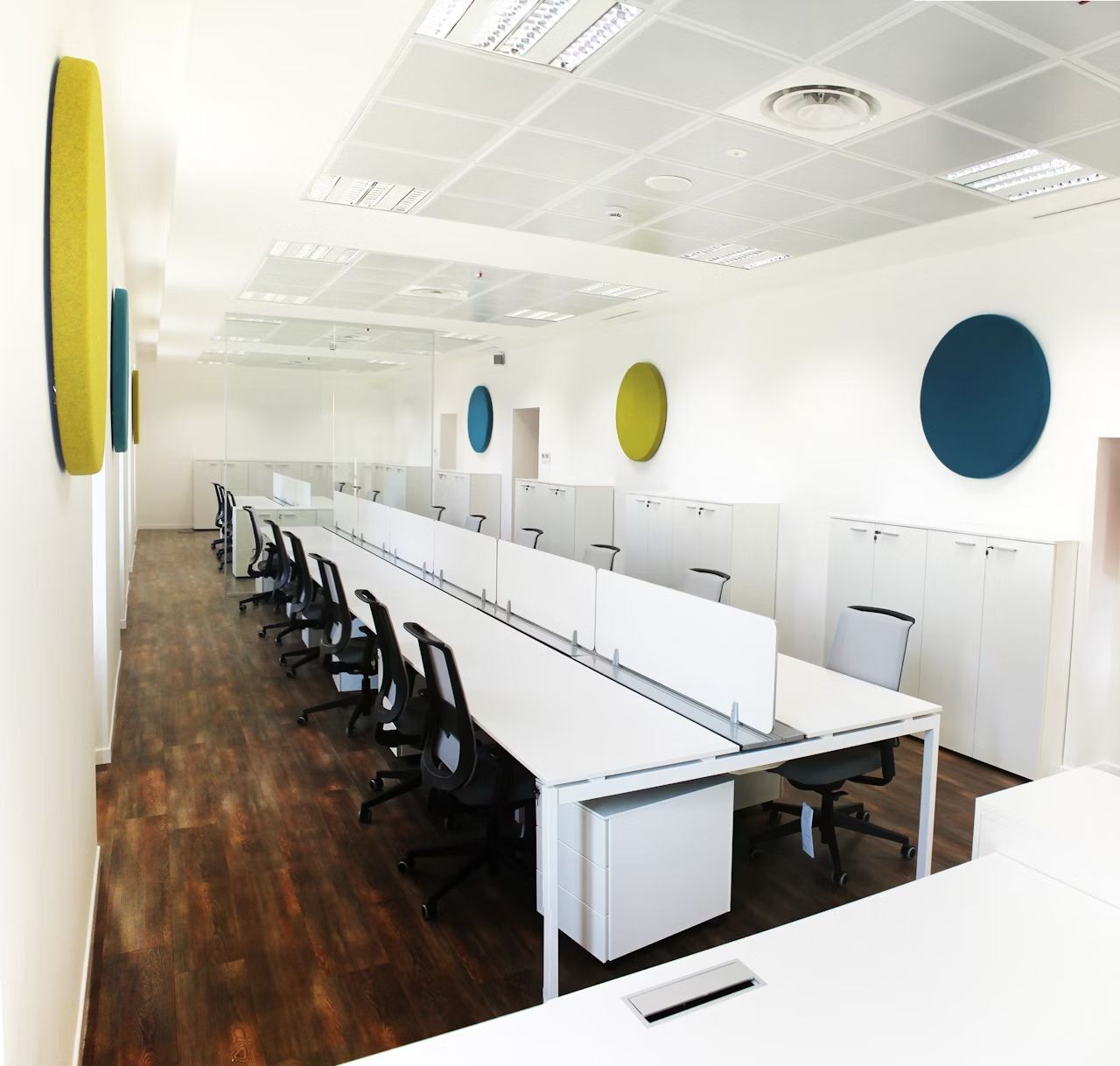 Moderne Großraumbüro mit ergonomischen Bürostühlen und weißen Tischen für dynamisches und gesundes Arbeiten.