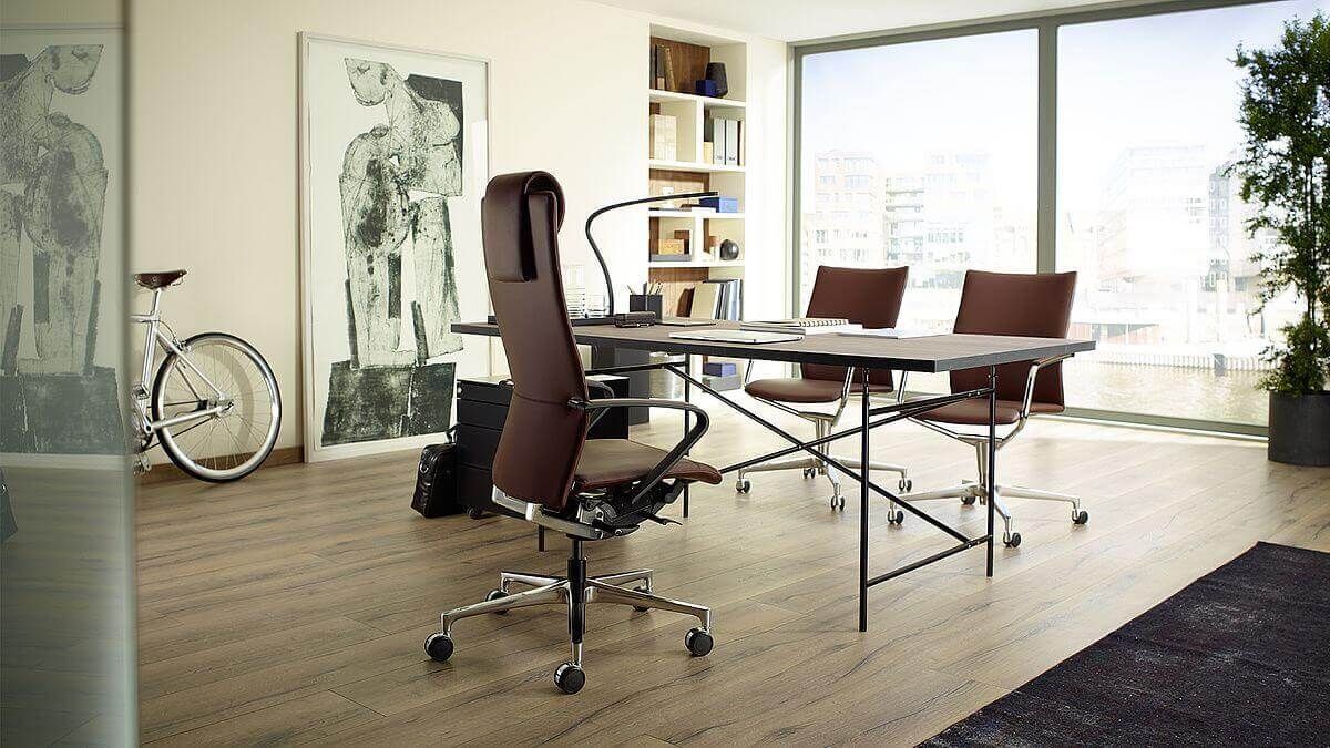 Modernes Büro mit ergonomischen Stühlen, großem Fenster und stilvollen Kunstwerken an den Wänden.